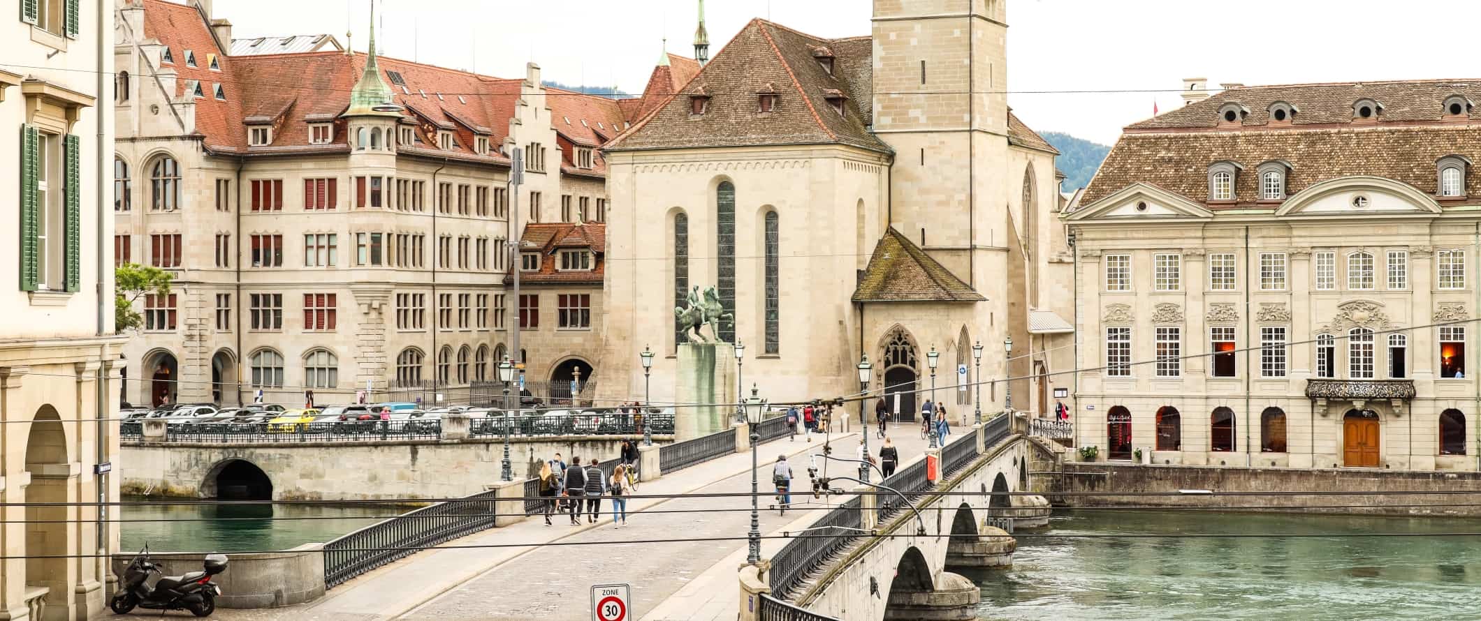 People walking across a stone bridge in the historic center of Zurich, Switzerland