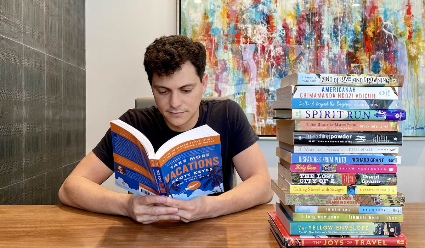 Nomadic Matt reading a stack of books about travel