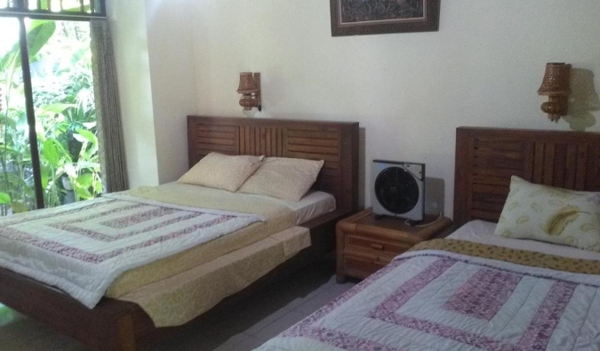 Two double beds and traditional Balinese furniture at Indraprastha guesthouse in Ubud, Bali