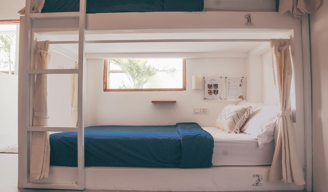 Tempat tidur susun bergaya kapsul putih dengan tirai privasi di hostel Arya Wellness di Bali