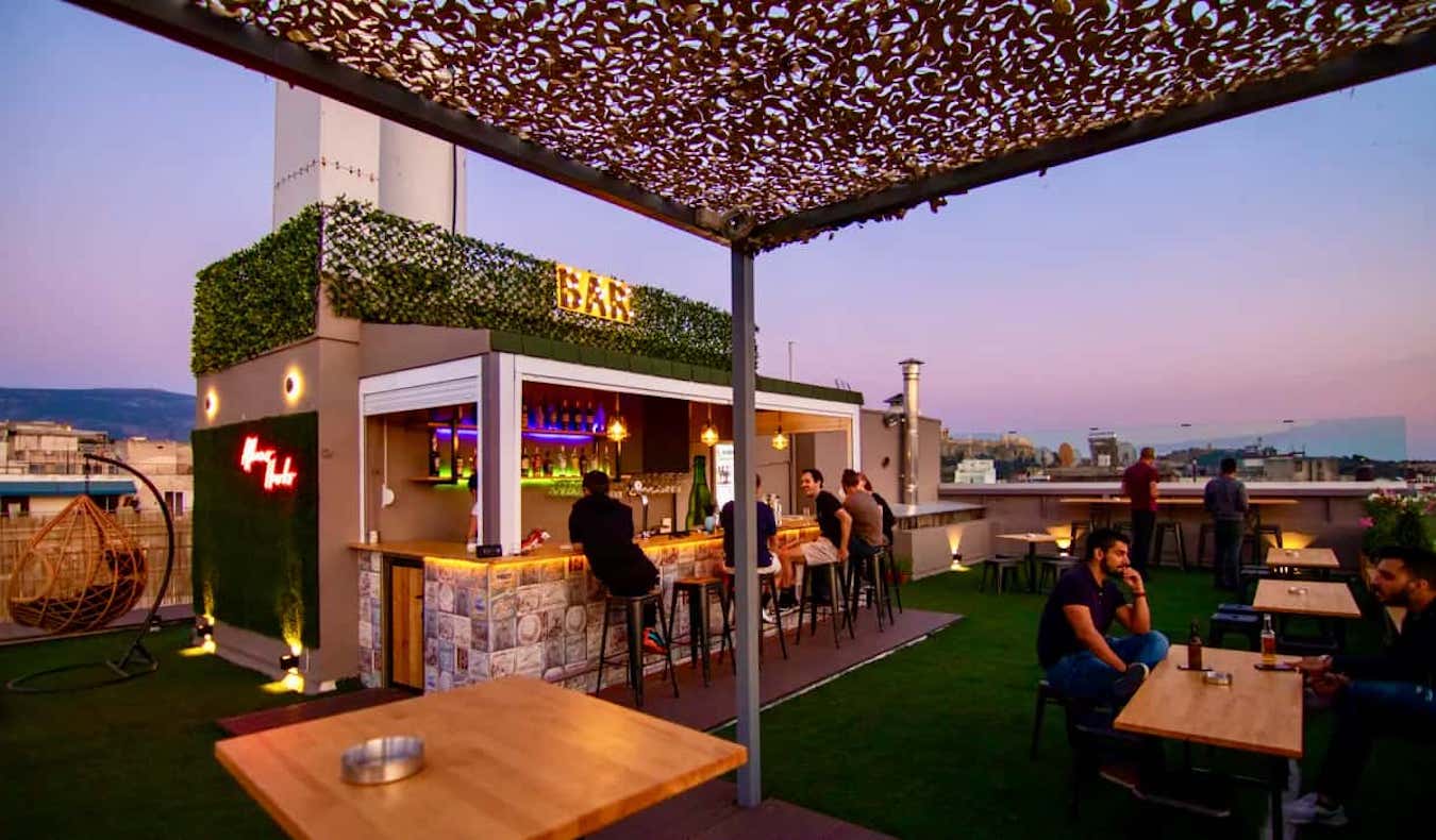 People hanging out on a rooftop bar at the Athens Hawks Hostel in Greece during sunset