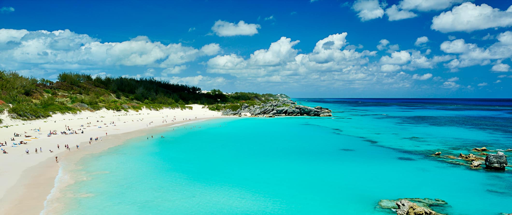 People lounging on a pristine beach with bright turquoise waters, on the beautiful coast of Bermuda