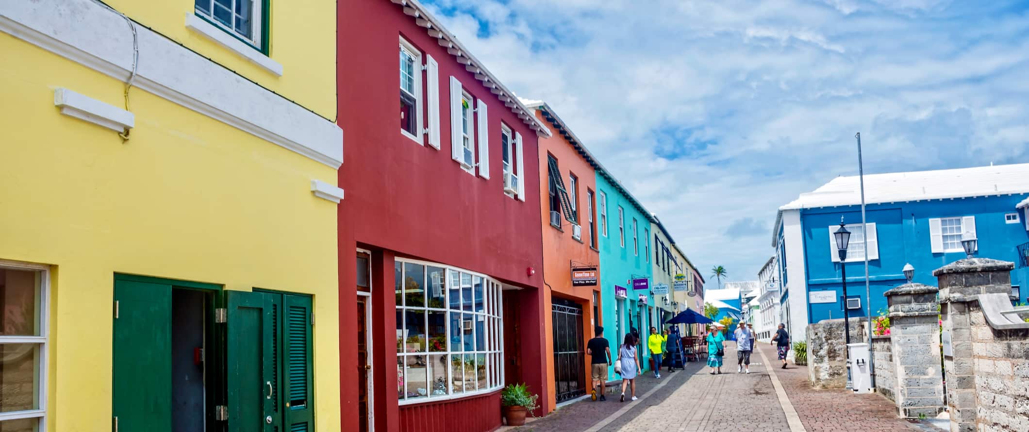 People walking down a pedestrianized street lined with brightly colored houses in Bermuda