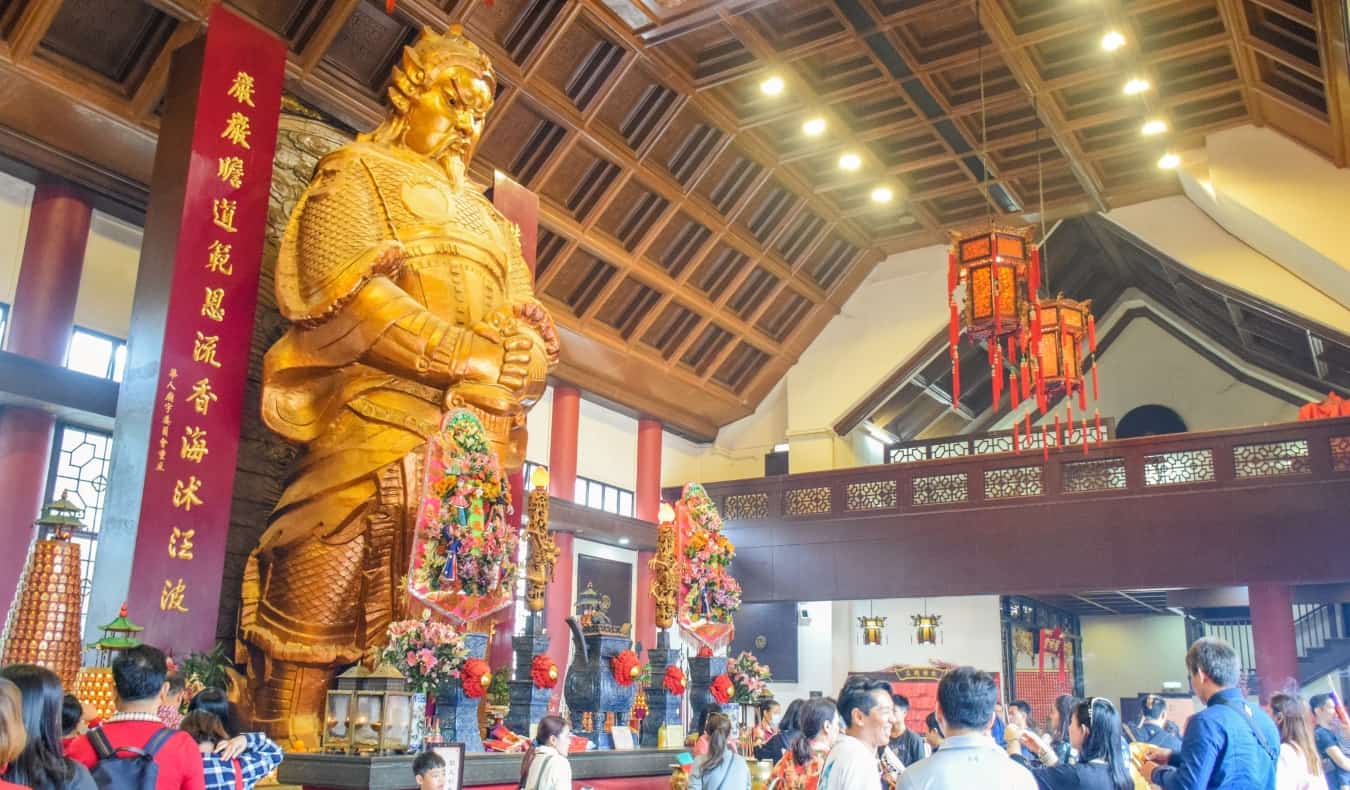The large golden statue of Commander Che Kung with people milling about in front of it at Che Kung Miu Temple in Hong Kong