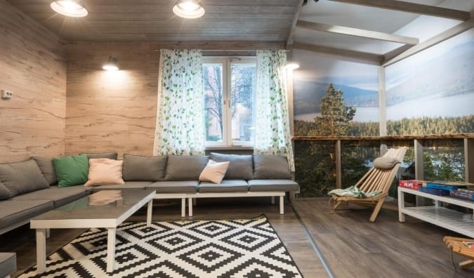 Espace commun de l'Eurohostel à Helsinki, en Finlande, avec des canapés gris recouverts de gros oreillers et une photographie à grande échelle d'un paysage ornant les murs