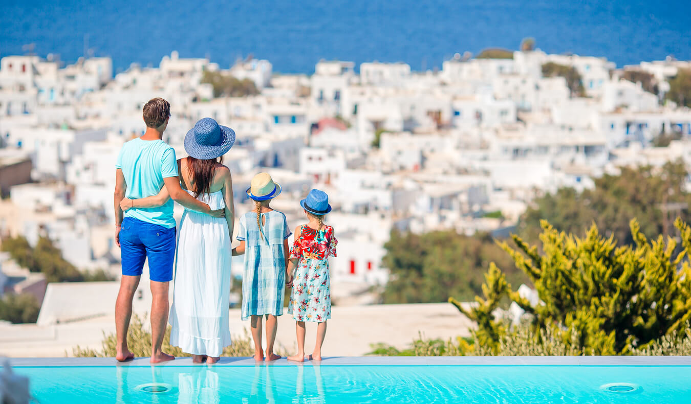 A traveling family at the pool standing near the water on an island in Greece