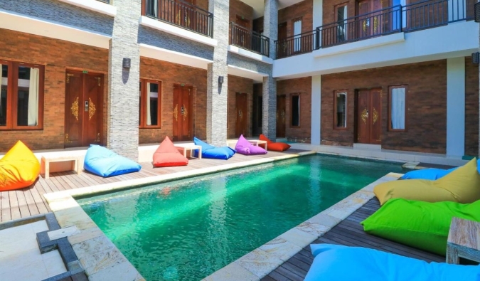 A long emerald swimming pool surrounded by colorful bean bags in the inner courtyard of Gelatik Bed & Breakfast in Seminyak, Bali.