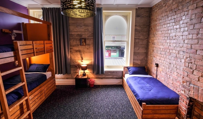 Tempat tidur kayu ganda di kamar dengan dinding bata di Haka Lodge di Auckland, Selandia Baru