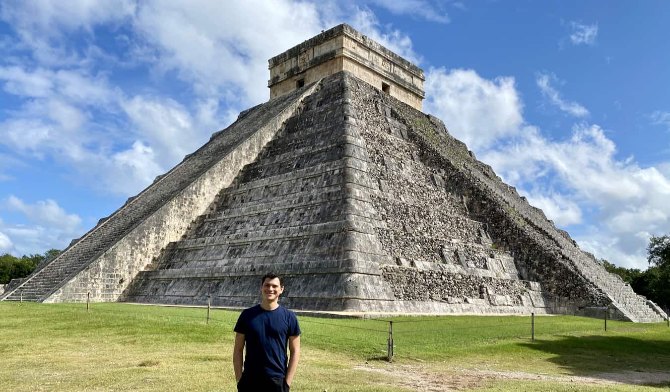 Nomadic Matt posing near the towering Chichen Itza pyramid in sunny Mexico