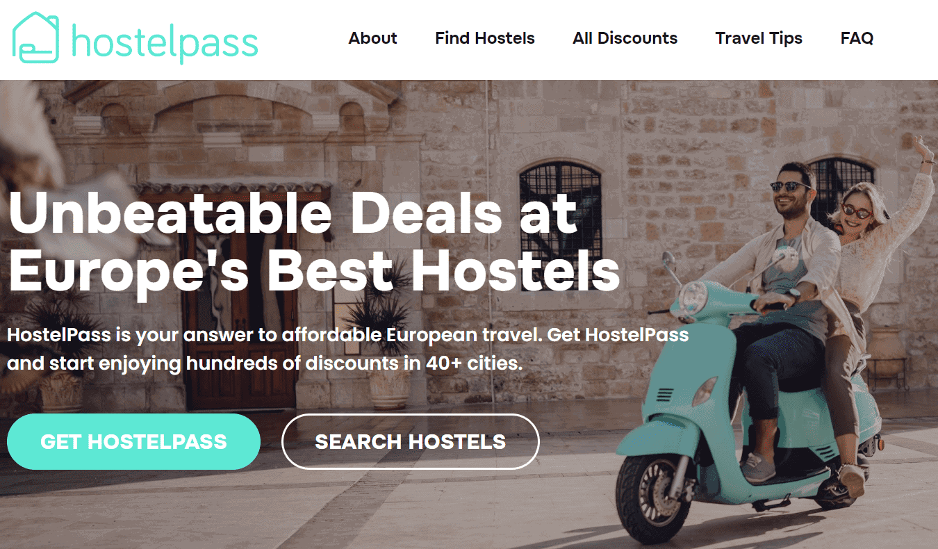 Capture d'écran de la page d'accueil du site Web de HostelPass avec un couple roulant sur une Vespa dans une rue pavée quelque part en Europe.