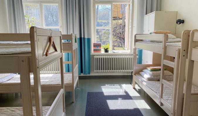 Dorm room at the Hostel Suomenlinna in Helsinki, Finland, with white wooden bunk beds and natural sunlight streaming in