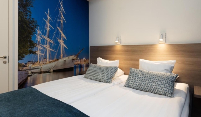Queen sized bed with a picture of a boat on the wall at Hotel Söder in Stockholm, Sweden