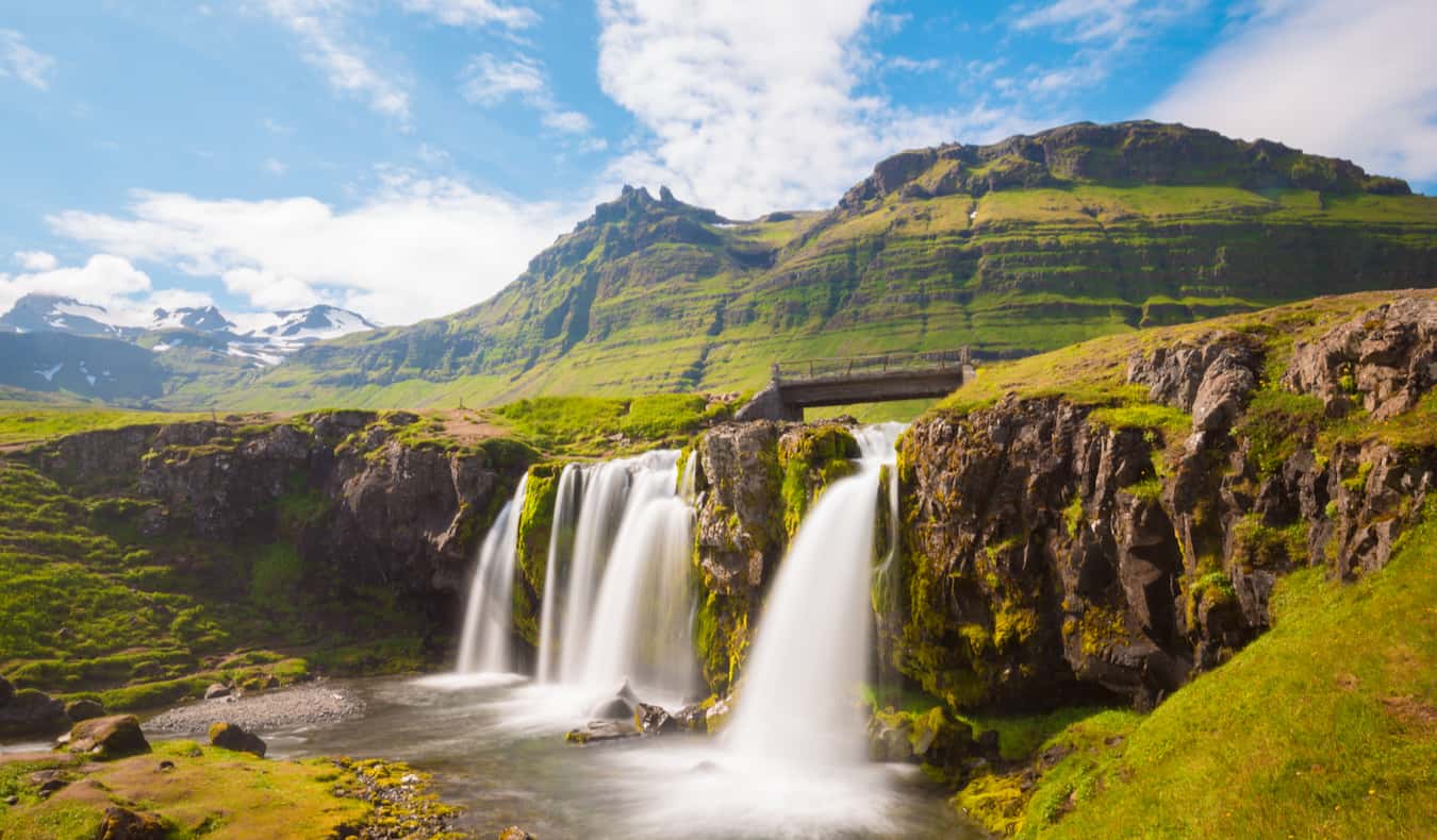 A beautiful waterfall beside a rugged landscape in sunny Iceland