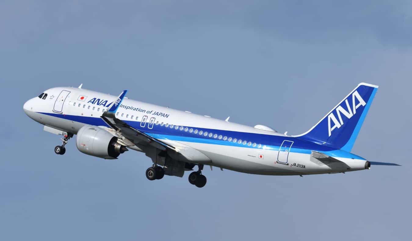 A plane flying through the sky with the ANA logo, a major airline in Japan