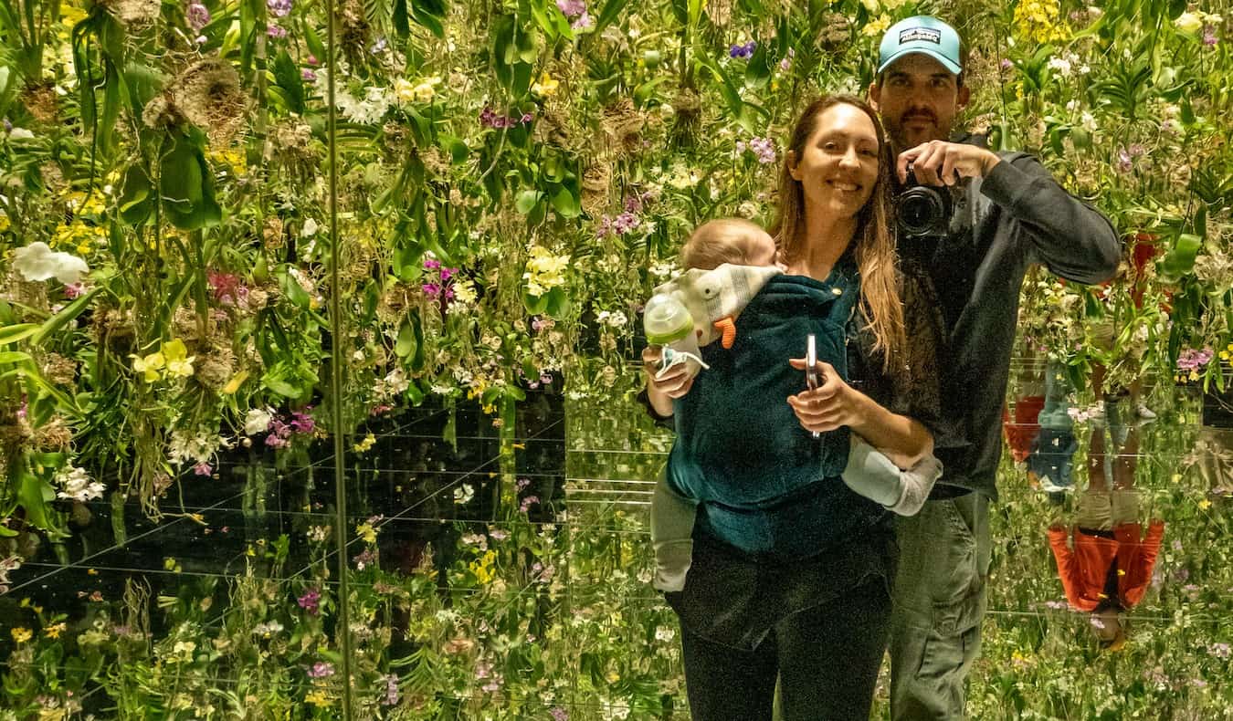 Blogger Kristin Addis of Be My Travel Muse with her partner and baby looking into the mirror at an art installation in Japan