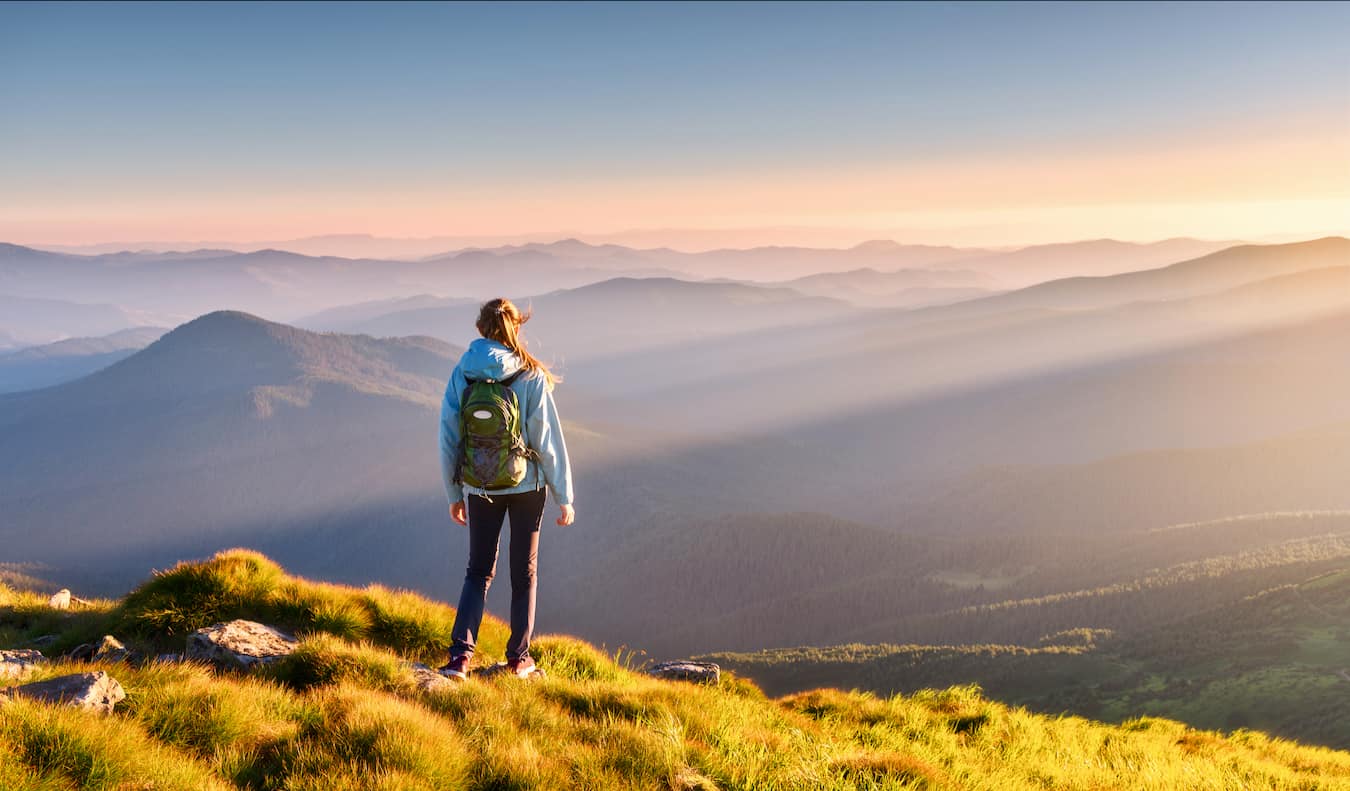 A solo female traveler hiking in the hills during sunset