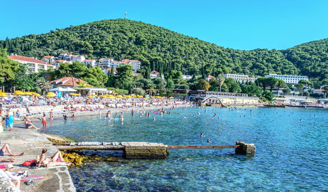 People lounging on Lapad Beach on a sunny day in Dubrovnik, Croatia