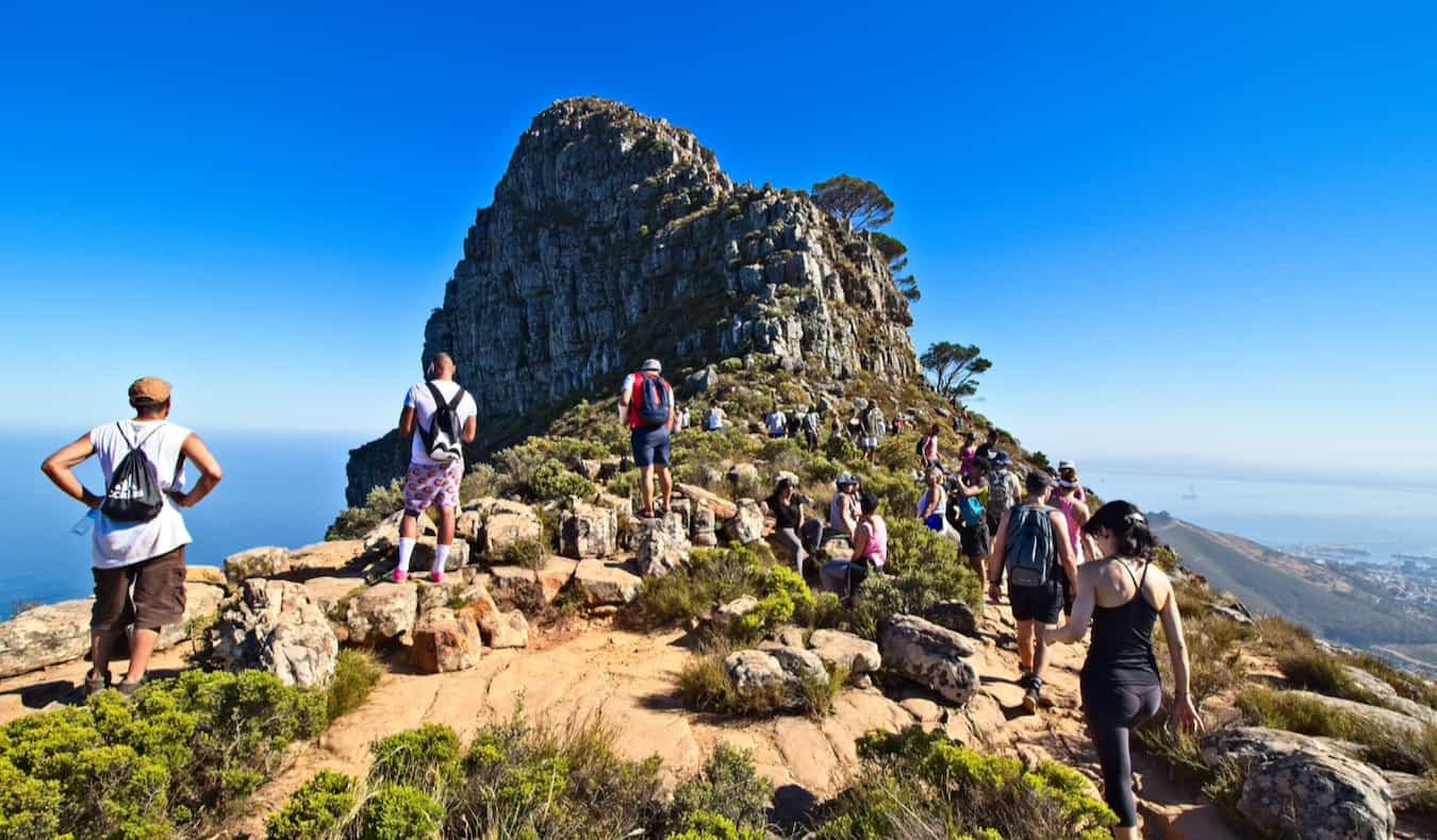 People hiking up Lions Head in Cape Town, South Africa on a bright and sunny day