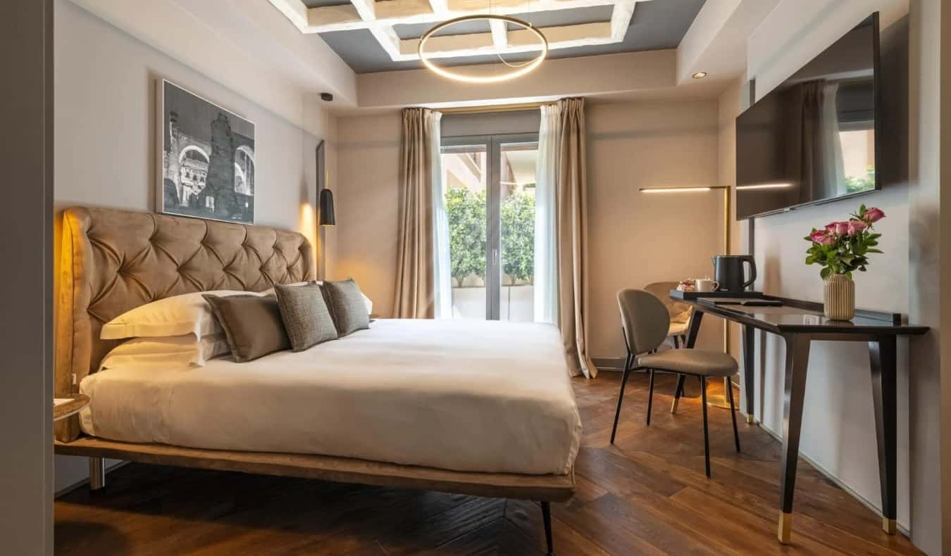 Large bed, desk, and TV on the wall at Loly Boutique Hotel in Rome, Italy