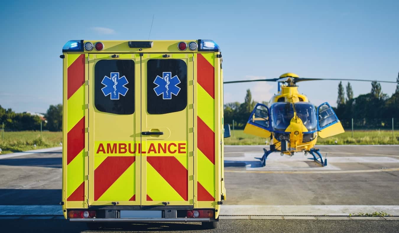 A yellow ambulance parked near an emergency helicopter