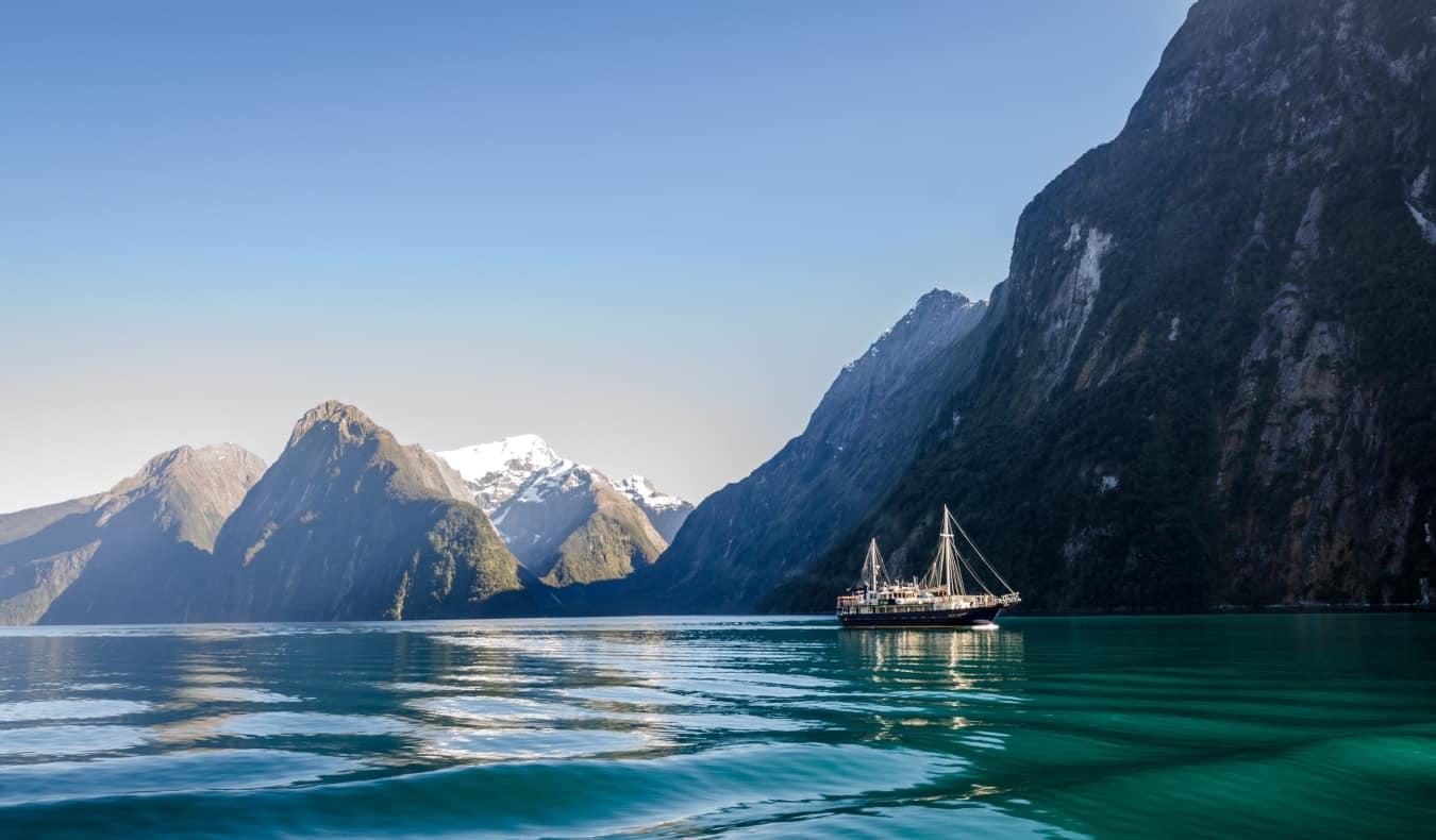 A  ship set against the sheer cliffs of Milford Sound in New Zealand