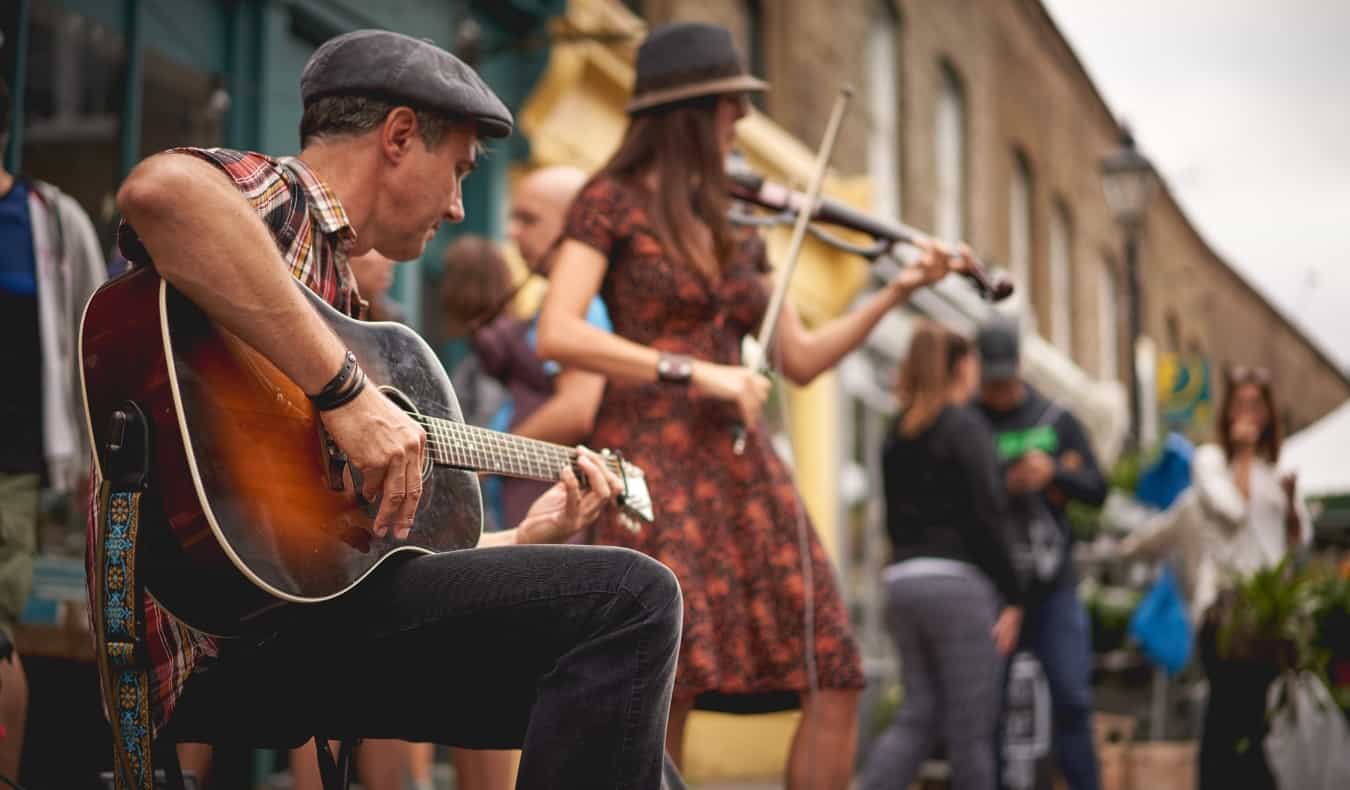 A guitarist and a violinist performing at the Columbia Road Flower Market in London, England