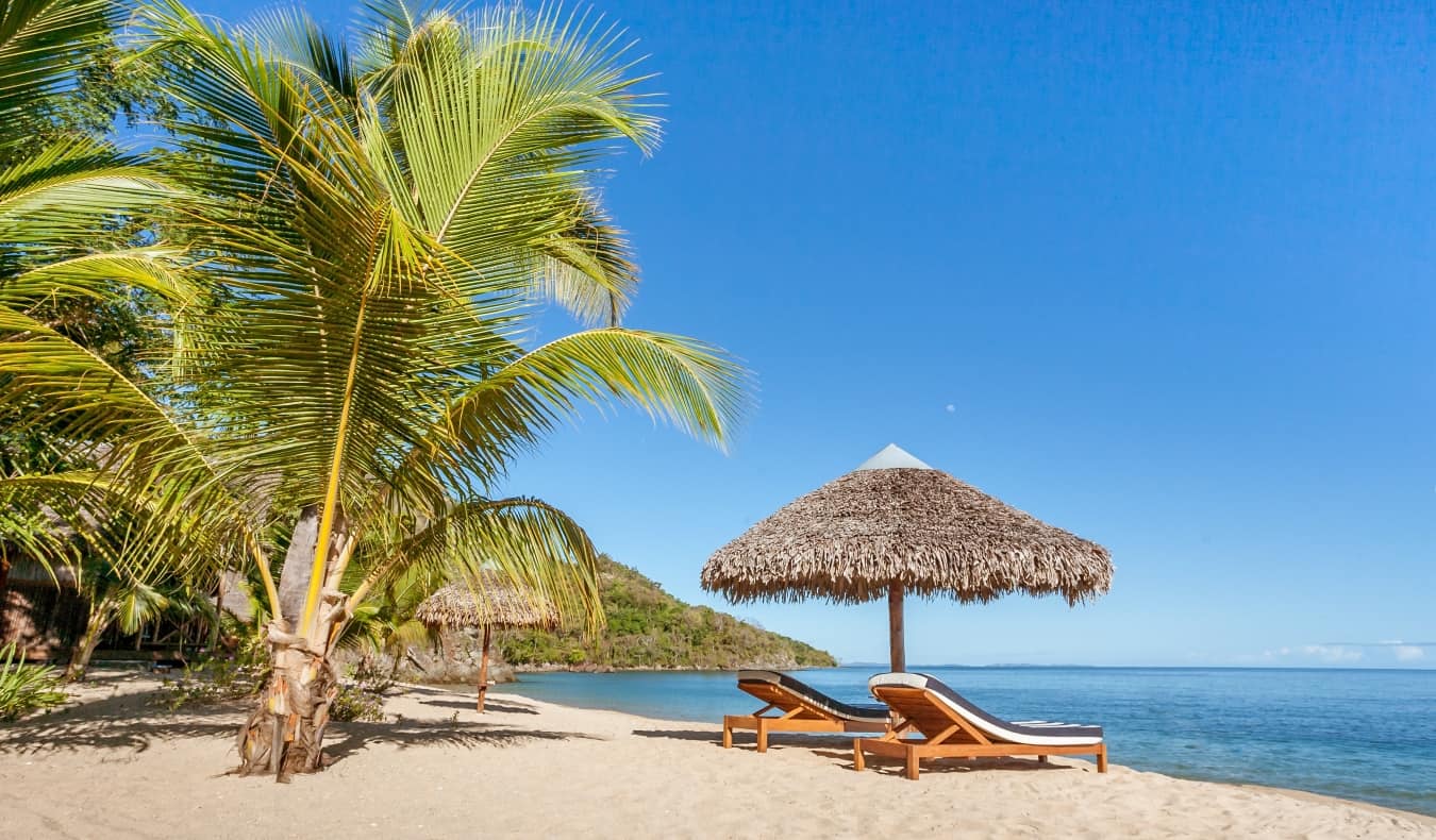 A white-sand beach with lounge chairs on it in Nosy Be, Madagascar