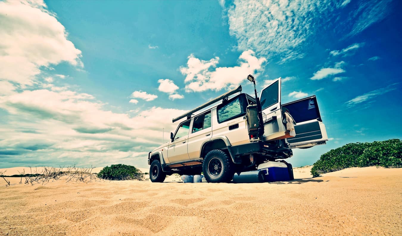 A rental jeep parked on the sand on a beautiful beach in sunny Australia