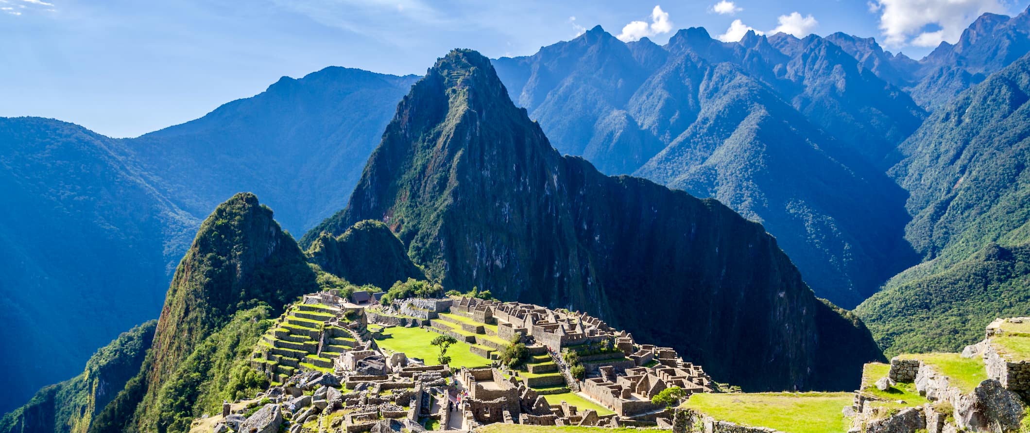 Machu Picchu, Peru with rolling mountains in the distance on a bright and sunny day