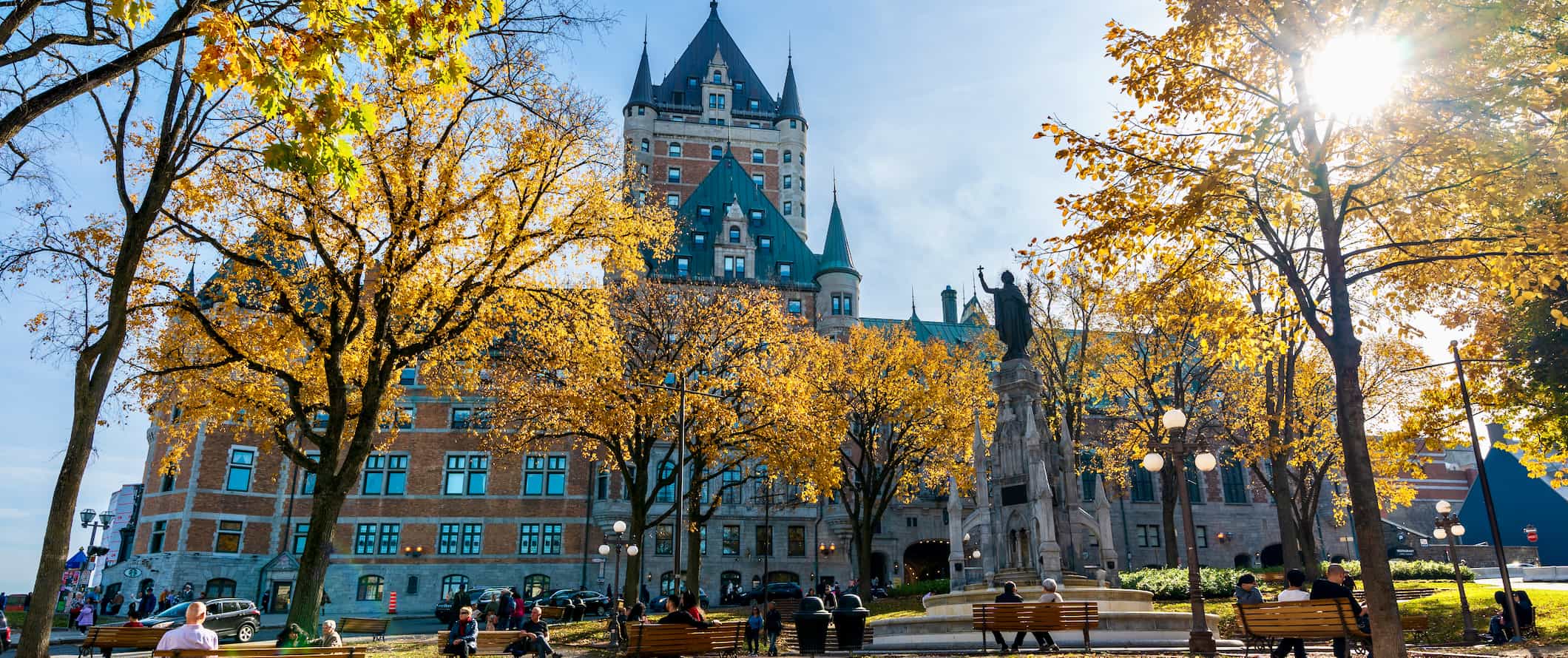 People relaxing in a sunny park near an old building in Quebec City, Canada