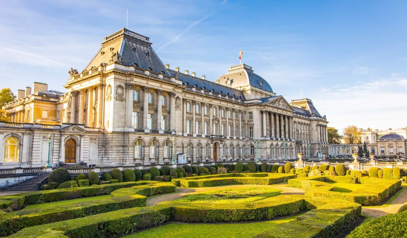 The stately exterior of the Royal Palace in Brussels, Belgium, with manicured gardens in front on a sunny day