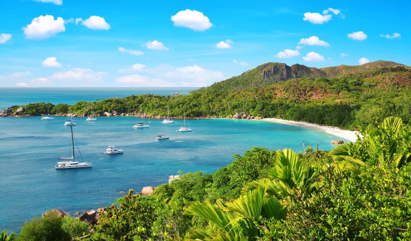 Sailboats in a tranquil bay surrounded by lush rolling hills in the Seychelles