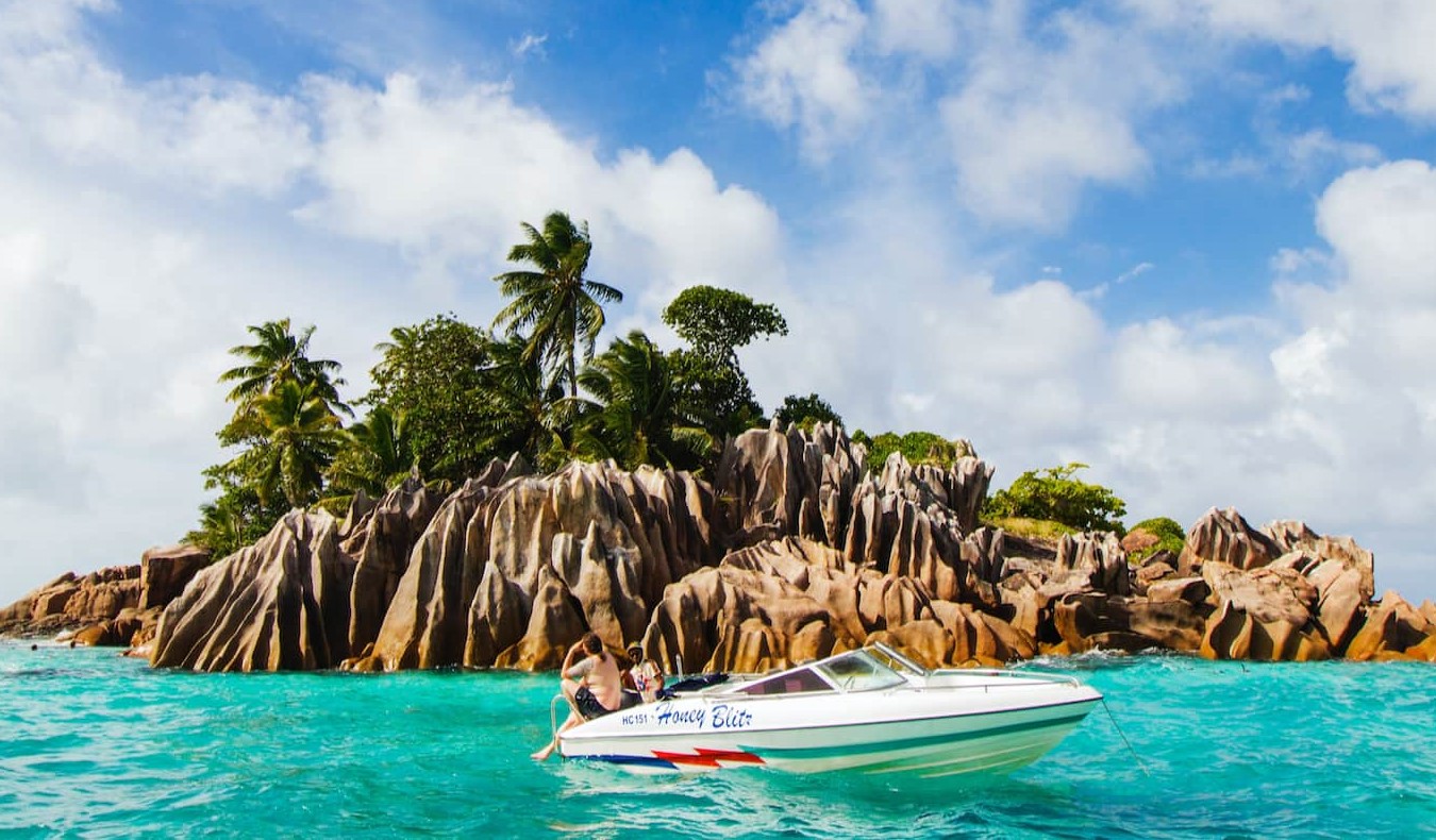 A boat anchored near a small island in the Seychelles during a beautiful sunny day