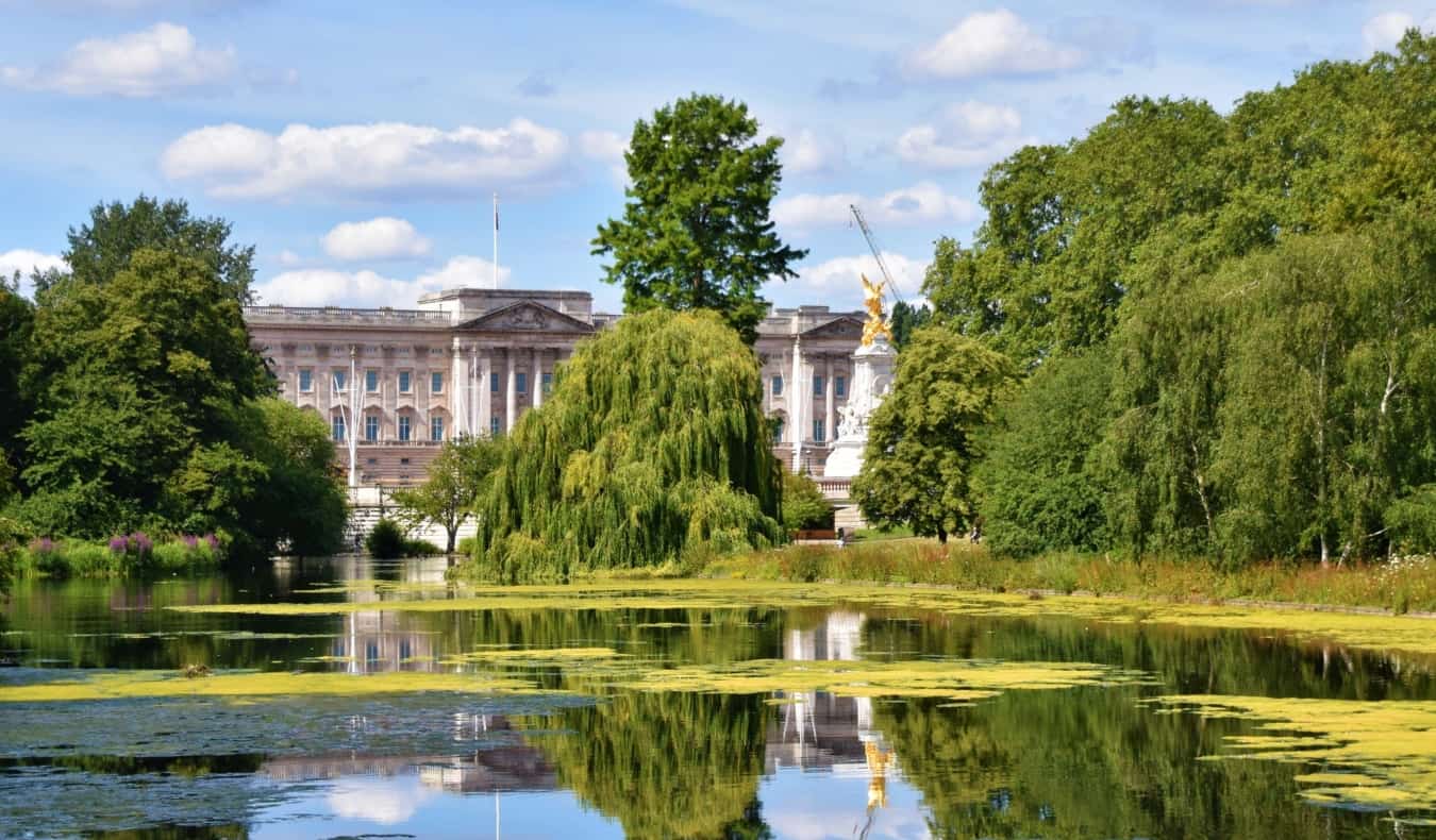 View of Buckingham Palace through the trees and behind a tranquil pond in St James Park in London, England
