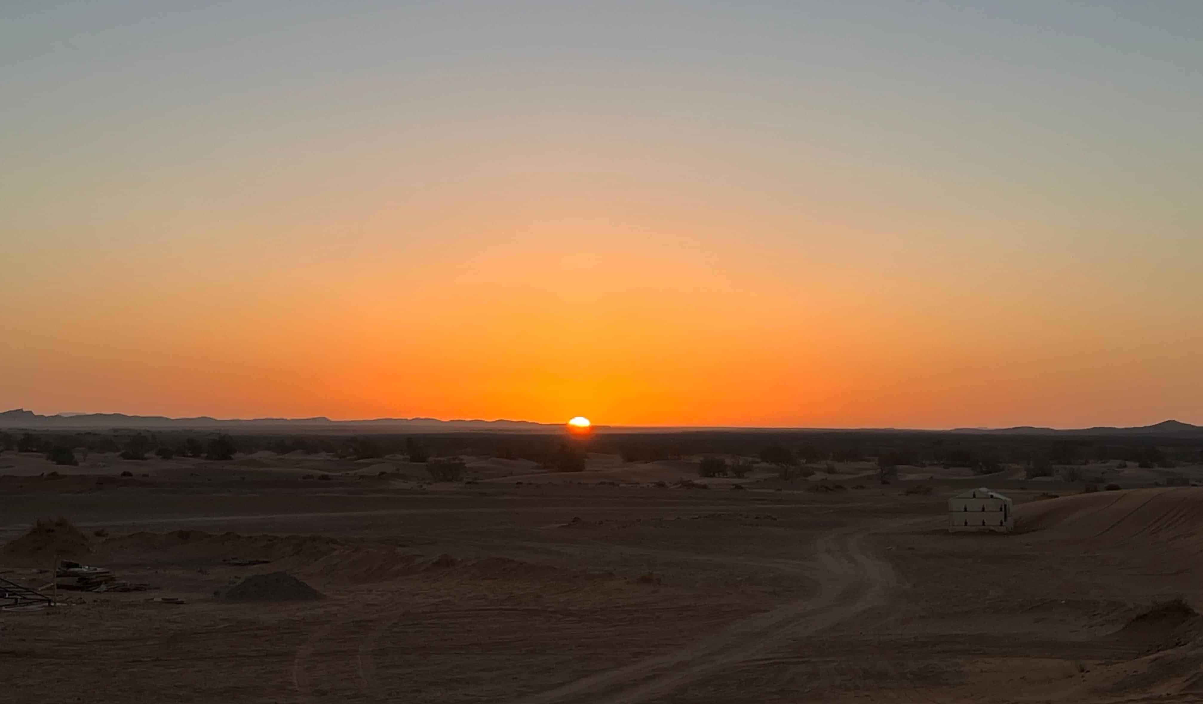 Red sand dunes covering the horizon in the Moroccan desert at sunset