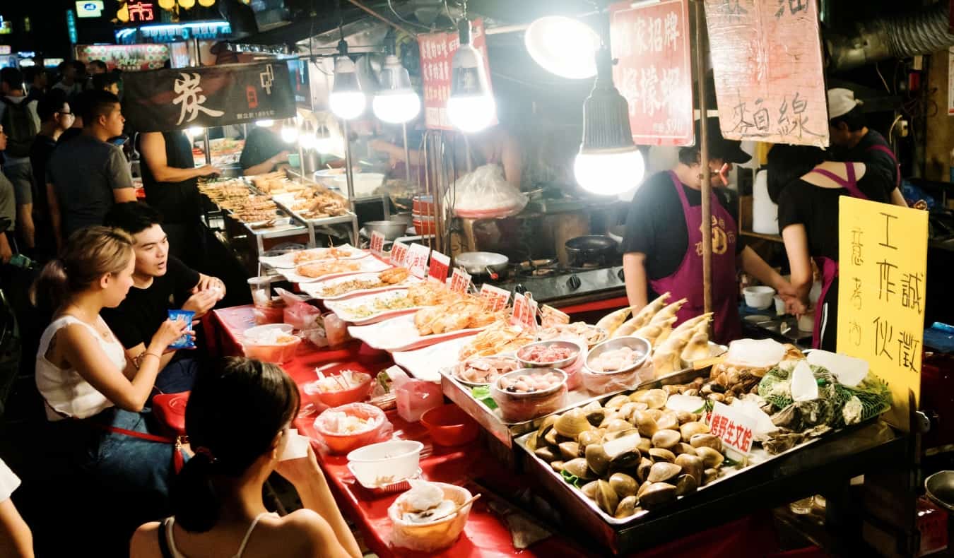 People eating at a street-side stall at Keelung Night Market in Taiwan