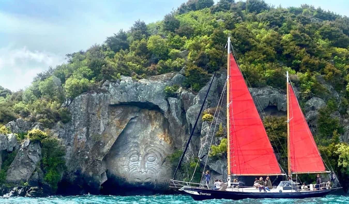 Red sailboat in front of a Maori rock carving on Lake Taupo in New Zealand