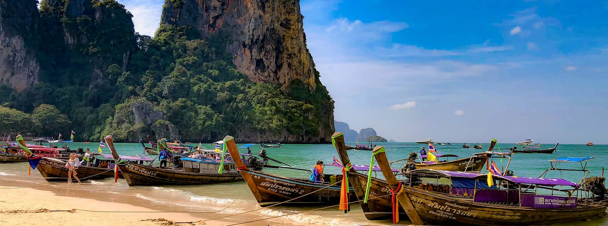 A row of longtail boats parked on a stunning beach in Thailand