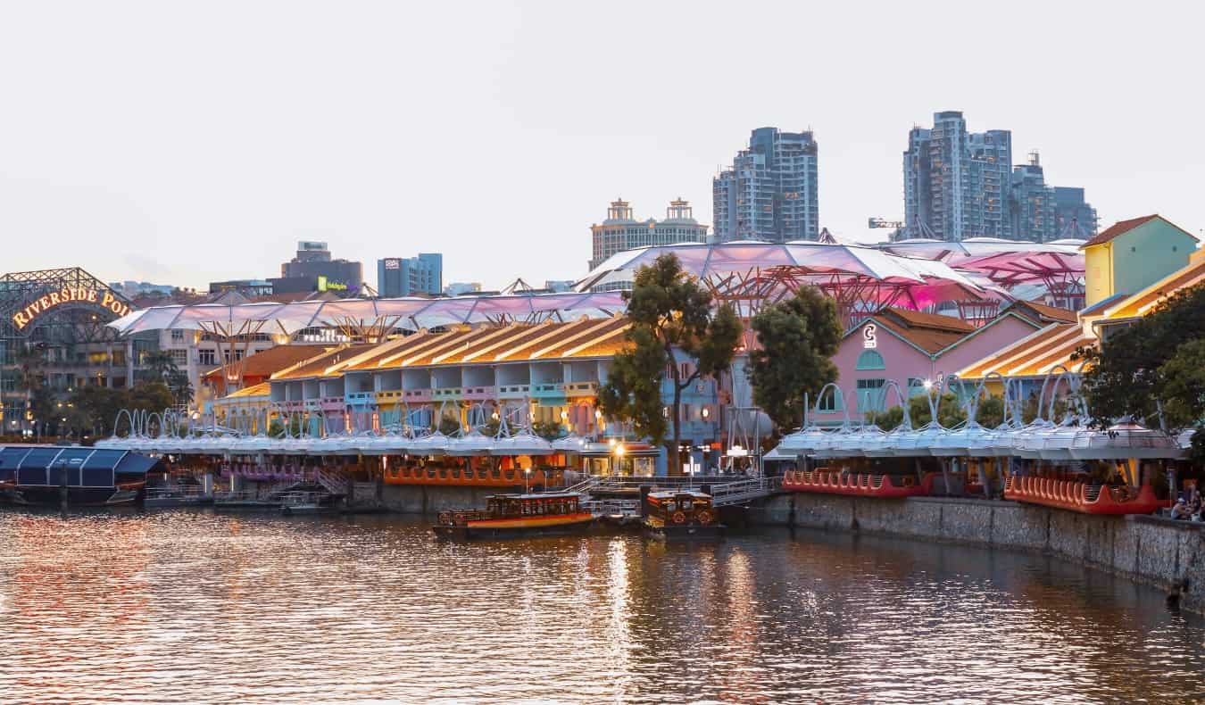 An evening scene with boats going by Clarke Quay in Singapore