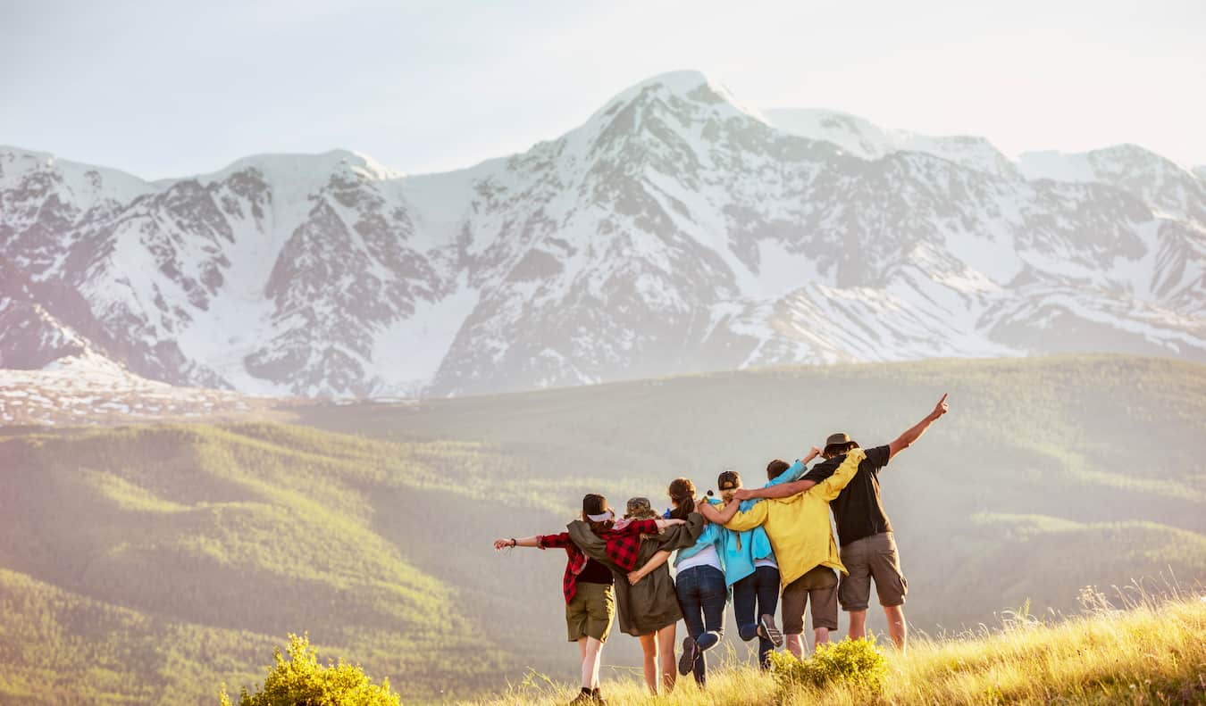 Un groupe de voyageurs en randonnée dans les montagnes d'une région accidentée posant pour une photo.
