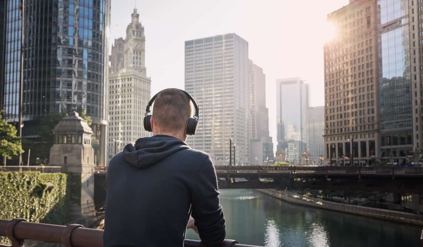 Man wearing a pair of over ear headphones while looking out over the skyline of Chicago