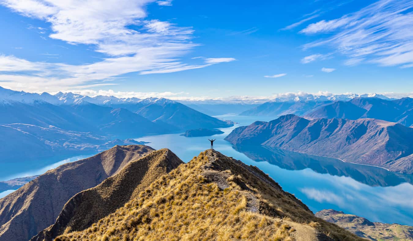 Un randonneur solitaire escaladant les collines de la Nouvelle-Zélande par une belle journée.