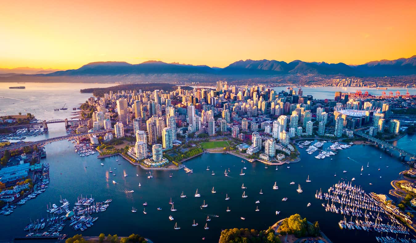the stunning skyline of Vancouver, Canada as seen from above at sunset with mountains in the distance