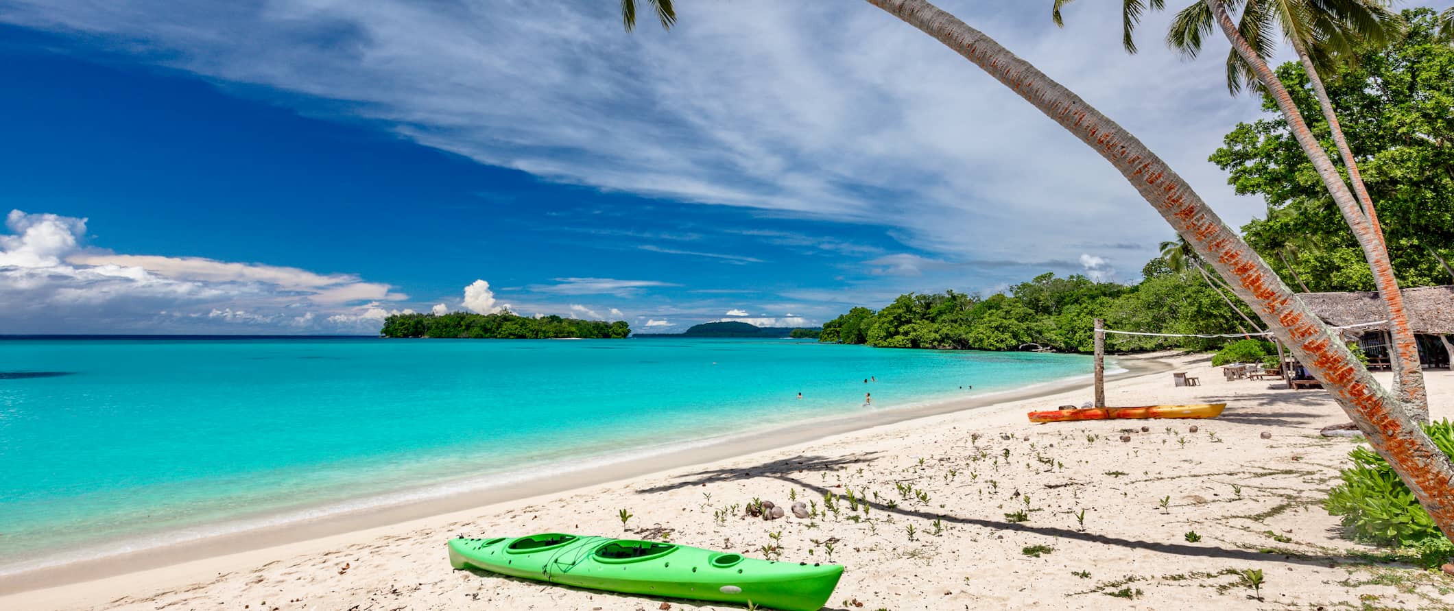 A sandy white beach in Vanuatu, with crystal-clear water and tropical plants framing the view