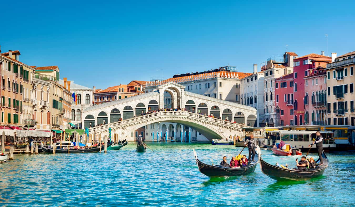 A sunny day in Venice, Italy as people ride gondolas down the grand canals