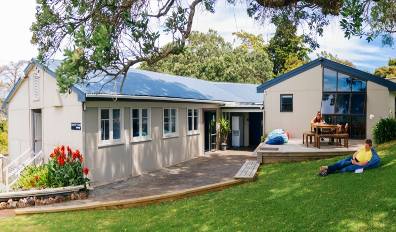 Njerëzit që rrinë në lëndinë përpara Hostel Waiheke Backpackers në Auckland, Zelanda e Re