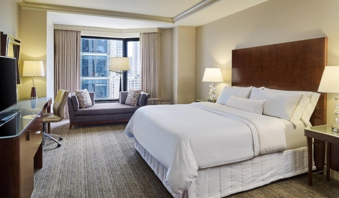 Crisp white king bed in a simple yet modernly designed room with a window view at the Westin Chicago River North Hotel