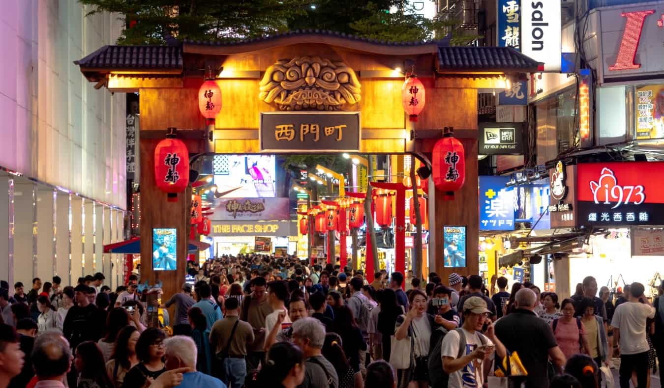 Crowds of people walk under a traditional archway in the Ximending neighborhood Taipei, Taiwan