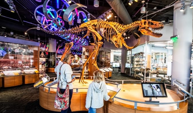 A mom and daughter stand in front of a dinosaur skeleton at the Museum of Natural Sciences in Raleigh, North Carolina
