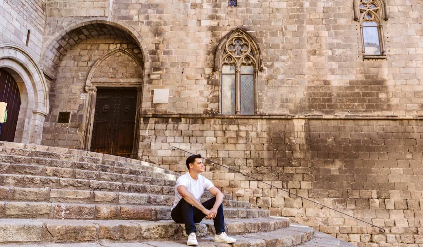 O nômade Matt sentado e pensando em uma velha e grande escadaria em Barcelona, ​​Espanha